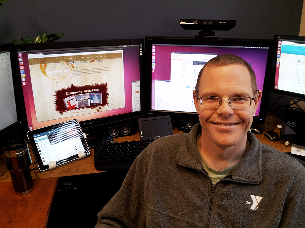 David at desk, surrounded by screens
